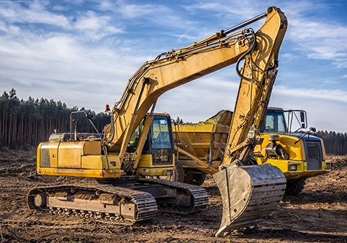 Gelber Kettenbagger und Muldenkipper auf einer Baustelle.