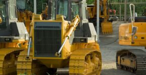 Gelbe Planierraupen und Bagger auf einem Auktionsgelände für Baumaschinen.