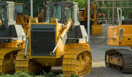 Gelbe Planierraupen und Bagger auf einem Auktionsgelände für Baumaschinen.