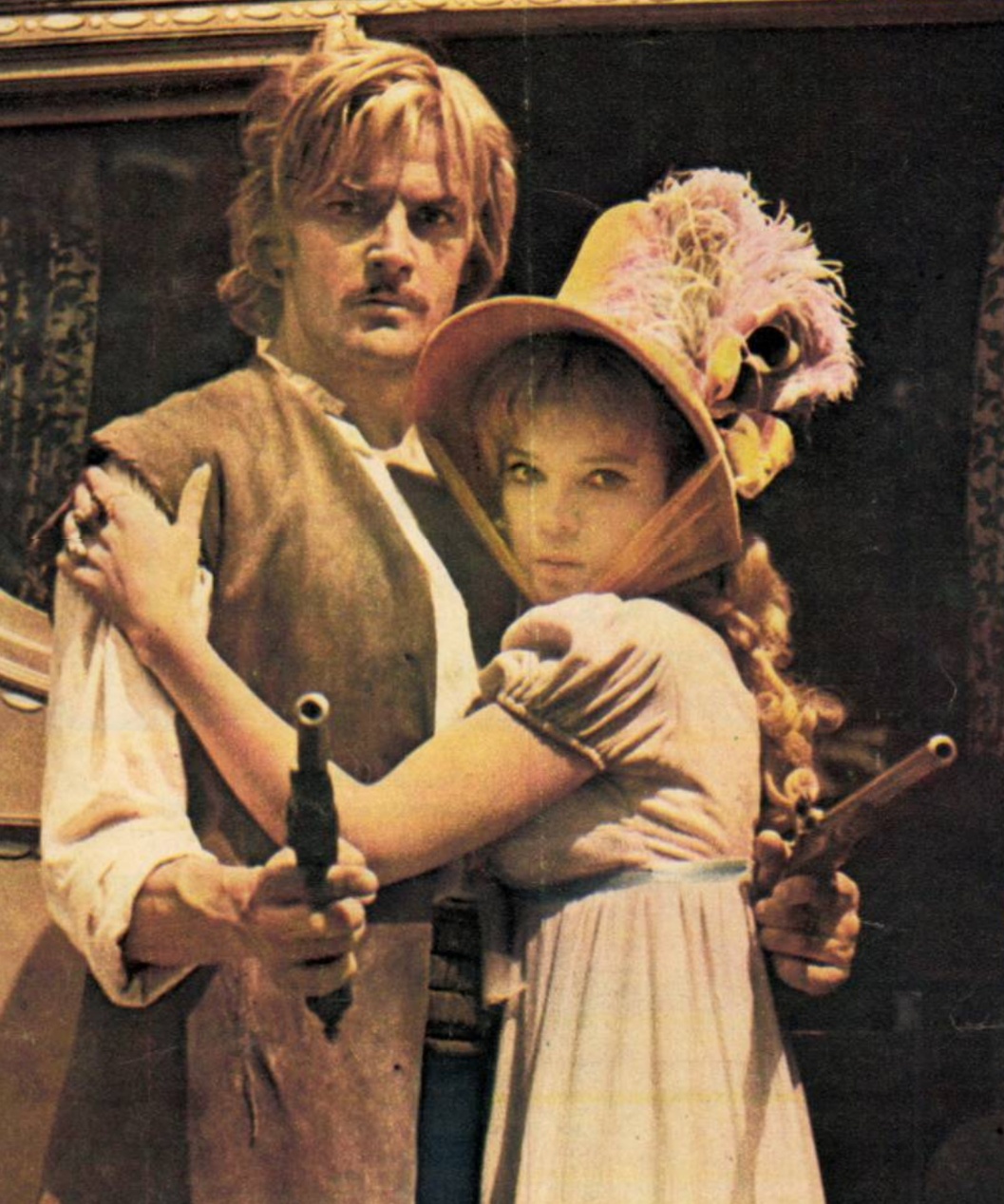 Eine Filmszene mit einem Mann und einem jungen Mädchen in aufwendigen historischen Kostümen, die die Bedeutung von Kleidung in Filmen unterstreicht.